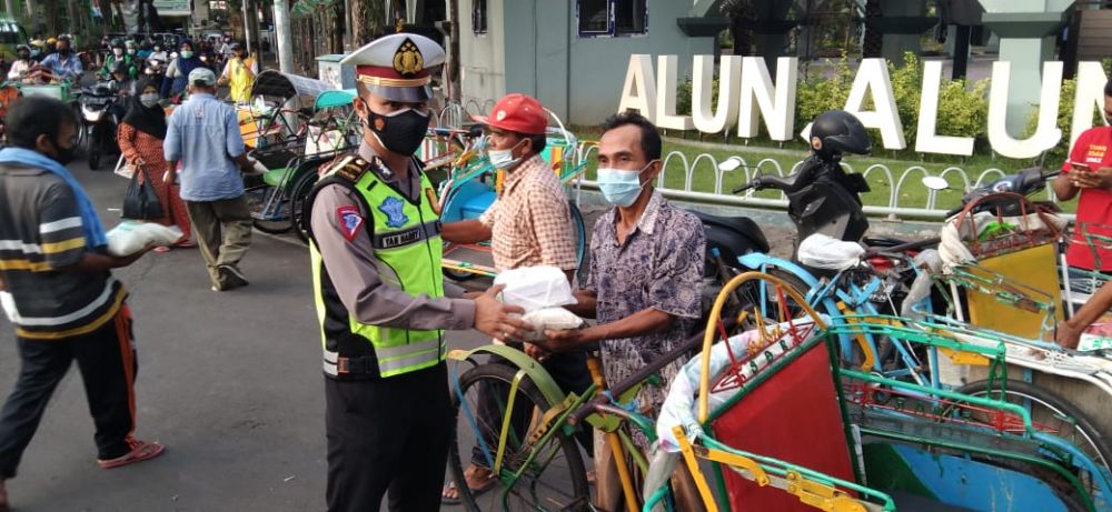 Anggota Satlantas Polres Gresik sedang berbagi Takjil, masker dan beras ke pejalan kaki dan pengendara yang lewat